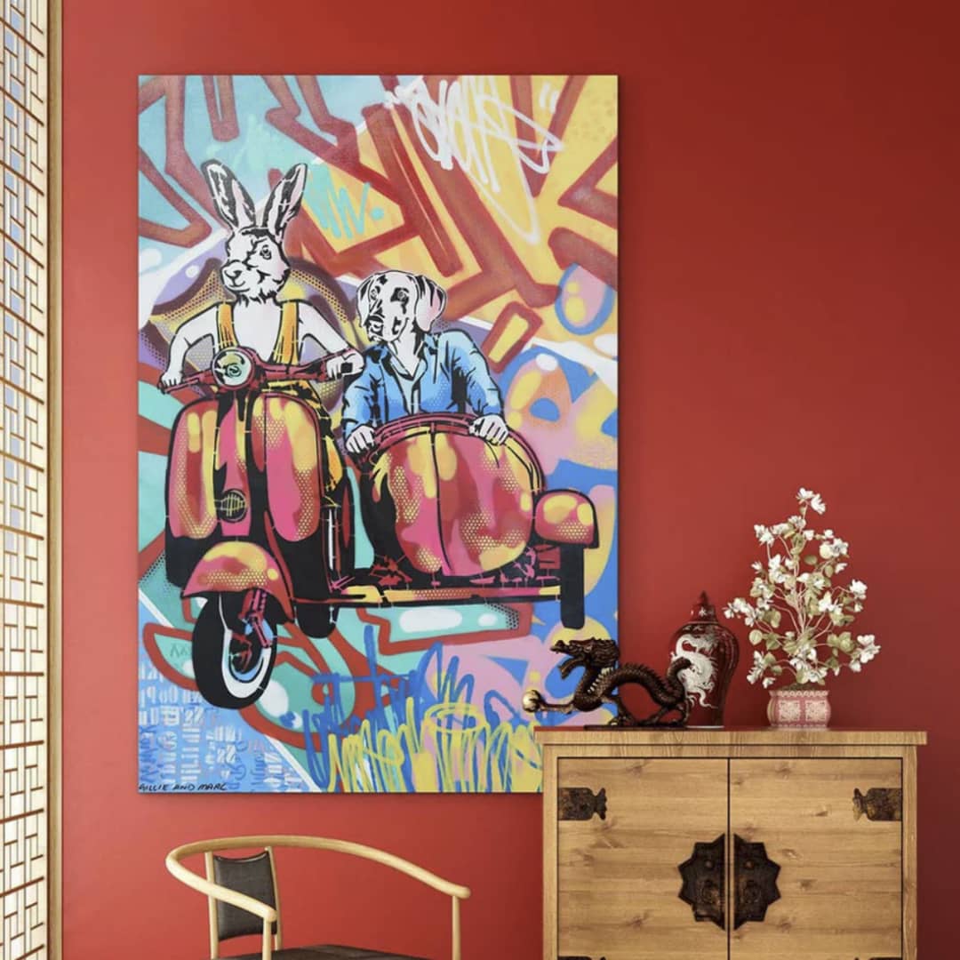 Gillie and Marc original painting ~ 'Just the Two of Us' @ Curate Art & Design in Daylesford, Gillie and Marc's premier gallery in Victoria, Australia.

Vibrant pop-art style illustration of a Rabbitwoman on a pink and yellow scooter with a Dogman in a sidecar, set against a colorful graffiti background.