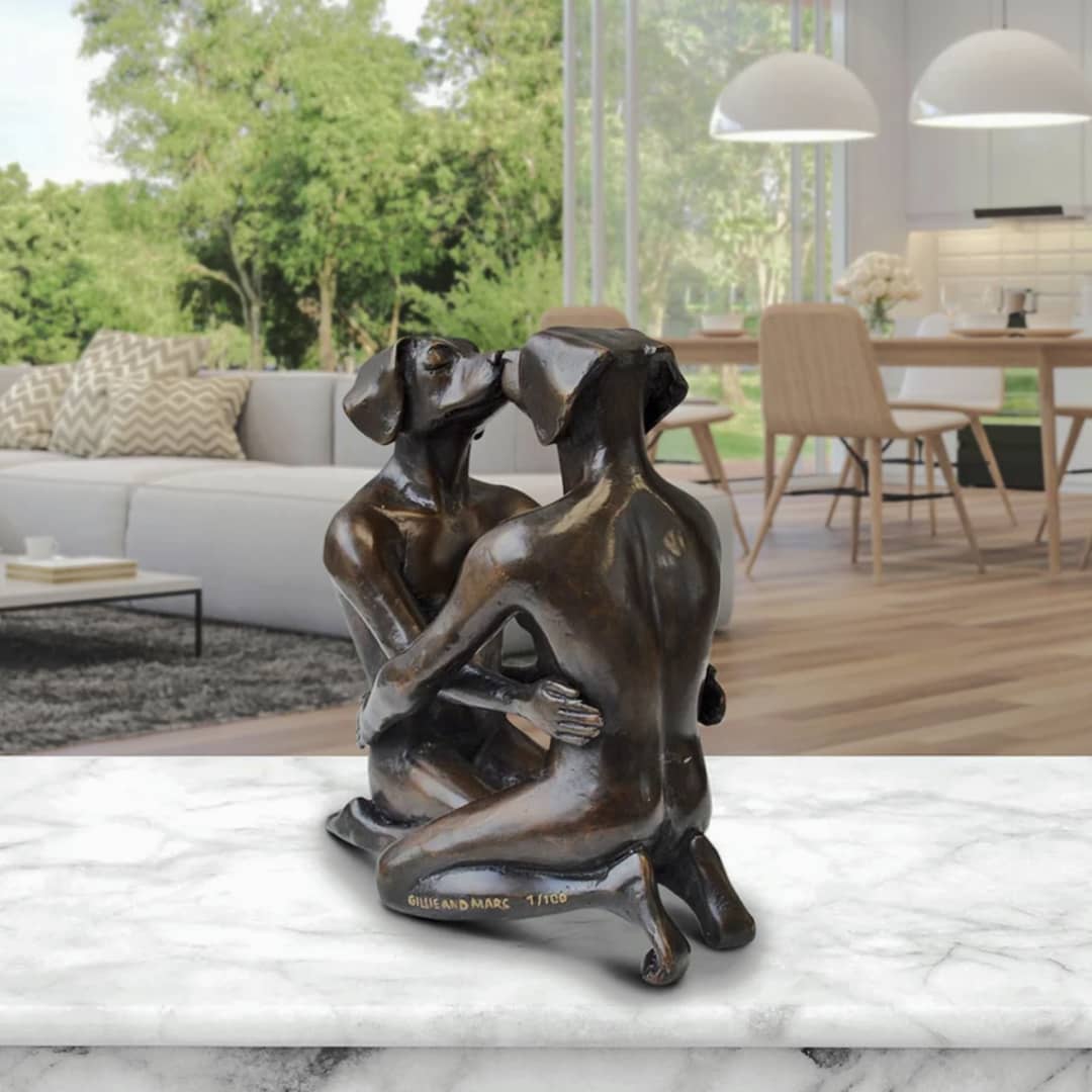 Gillie and Marc Sculpture ~ 'He Fell in Love with Him Again and Again' @ Curate Art & Design, Gillie and Marc's premier gallery in Daylesford (former Sorrento), Victoria.
Bronze sculpture of two people embracing on a marble surface with a modern living room in the background.