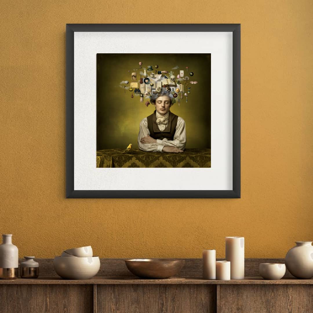 Maggie Taylor Art ~ 'A Thousand Words' 22" (Framed) - Available in Australia @ Curate Art & Design in Daylesford. Free delivery to Melbourne. 

A framed art print featuring a surrealist portrait of a man with a small yellow bird on his shoulder, set against a dark olive background with floating miscellaneous objects above his head. The print is presented with a white mat and a black frame.