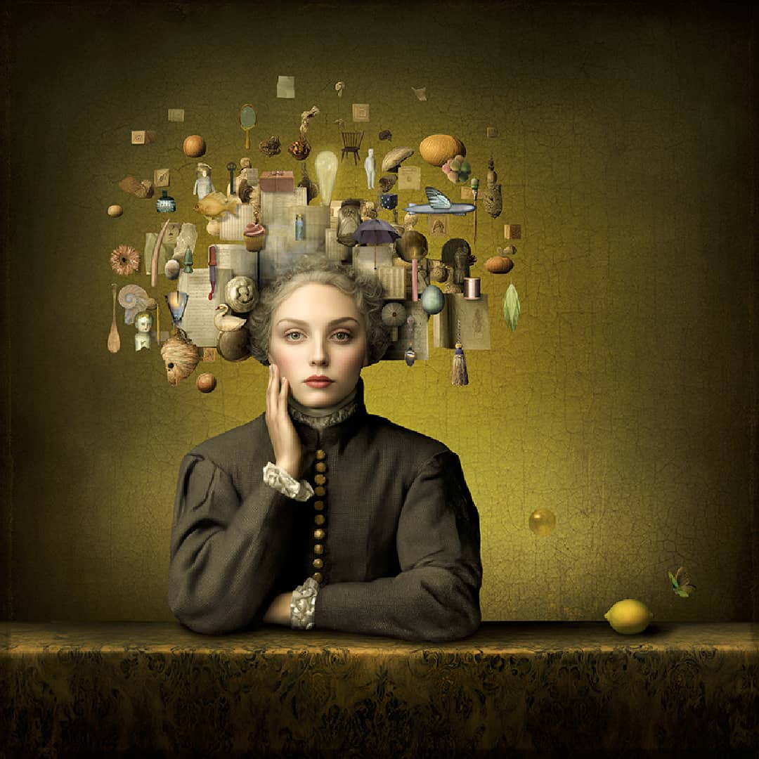 Maggie Taylor Art ~ 'Typical Tuesday' 22" (Framed) - Available in Australia @ Curate Art & Design in Daylesford. Free delivery to Melbourne.

A surreal portrait of a woman in a dark brown dress sitting at a table against a textured olive-green background, with a floating collage of everyday objects and small figures emerging from her head. A yellow fruit rests on the table to her right.